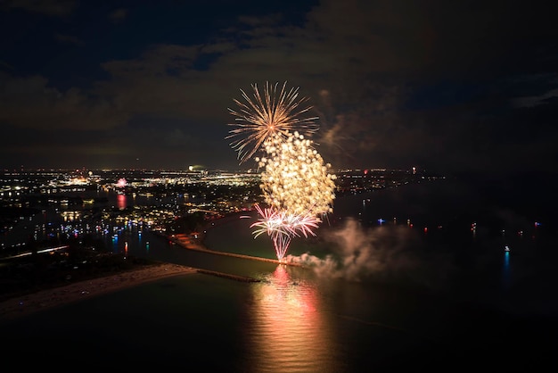 Vue aérienne de feux d'artifice lumineux explosant avec des lumières colorées au-dessus du bord de mer le jour de l'indépendance des États-Unis