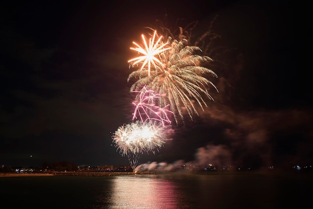 Vue aérienne de feux d'artifice lumineux explosant avec des lumières colorées au-dessus du bord de mer le jour de l'indépendance des États-Unis