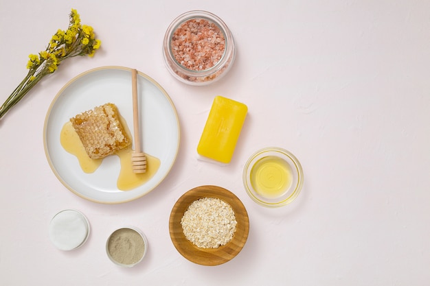 Une vue aérienne de la fleur jaune; des tampons de coton; L&#39;avoine; huile essentielle; savon et sel rock himalayen sur fond texturé blanc