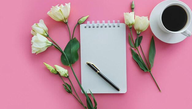 Une vue aérienne de fleurs d'eustome avec un stylo de carte de journal et une tasse de café sur un fond rose