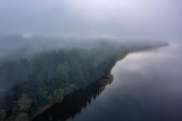 Vue aérienne de la forêt au bord du lac couvert d'un épais brouillard Carélie Russie