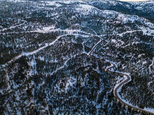 Vue aérienne de la forêt enneigée avec une route capturée d'en haut avec un drone