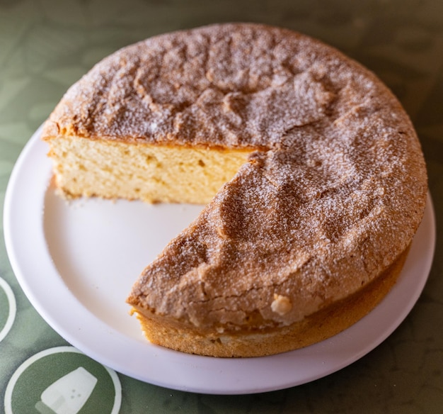 Vue aérienne d'un gâteau santiago incomplet avec une tranche manquante sur une plaque blanche dans un cadre carré