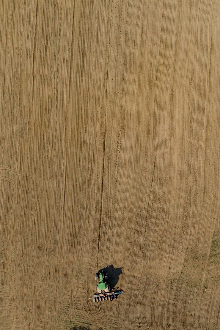 Photo vue aérienne grand tracteur cultivant un champ sec.