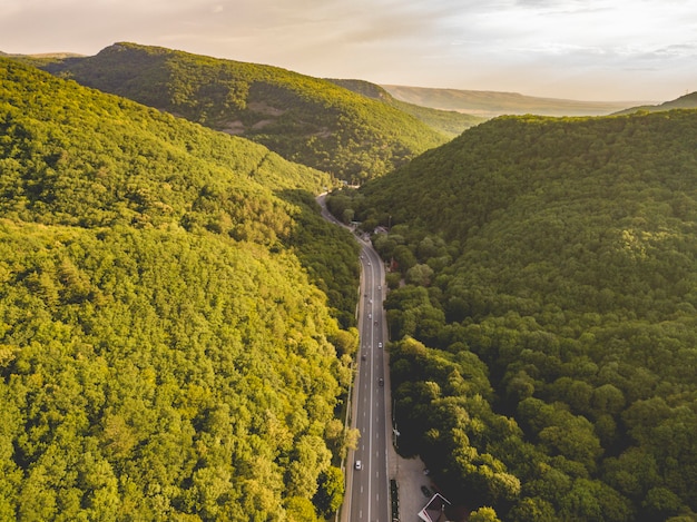 Vue aérienne de la grande route entre les montagnes couvertes de bois verts