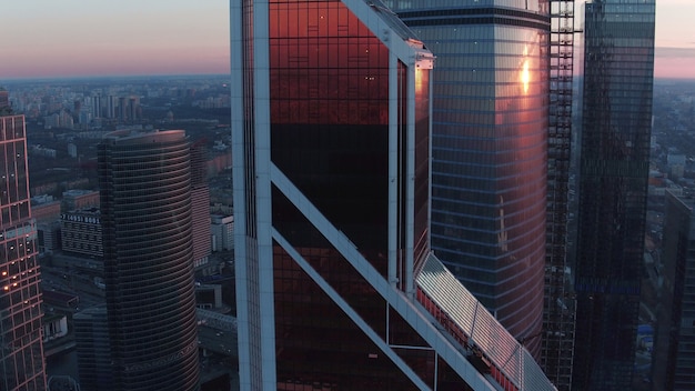 Une vue aérienne des gratte-ciel du quartier de la ville de Moscou, reflétant le ciel coloré du soir. L'arrière-plan urbain est rempli de bâtiments, légèrement flous sur l'horizon rose