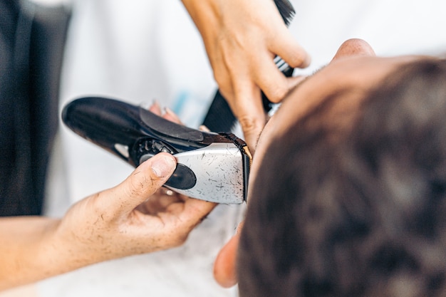 Vue aérienne en gros plan d'un rasoir électrique en métal utilisé pour raser un client dans un salon de coiffure