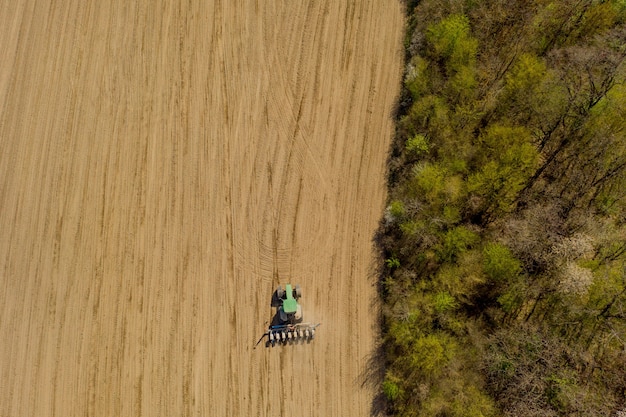 Vue aérienne gros tracteur cultivant un champ sec. Vue aérienne de haut en bas du tracteur cultivant le sol et ensemencant un champ sec.