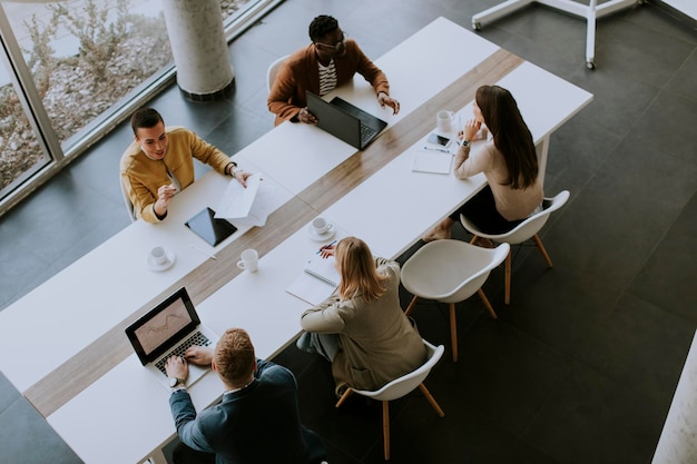 Vue aérienne d'un groupe de jeunes hommes d'affaires multiethniques travaillant ensemble et préparant un nouveau projet lors d'une réunion au bureau