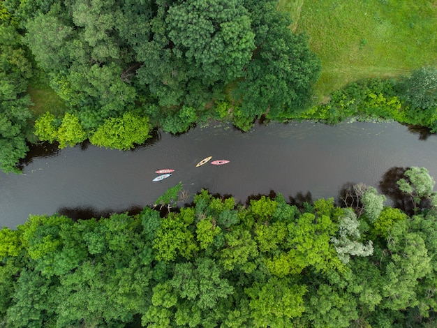 Vue aérienne d'un groupe de kayaks voyageant sur une rivière forestière un jour d'été
