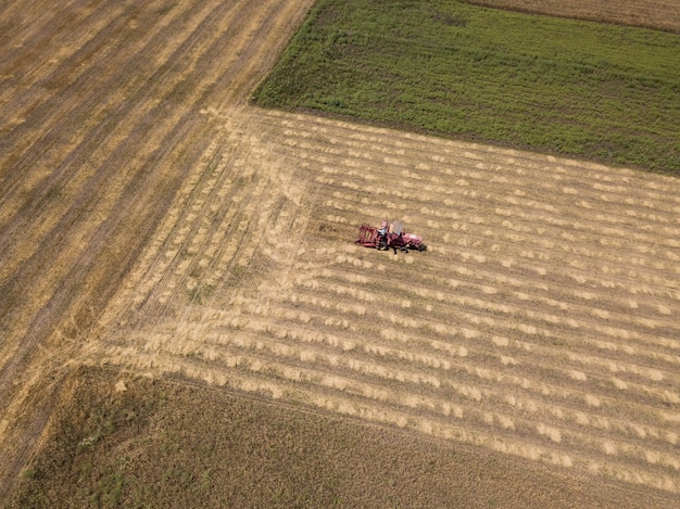 Vue aérienne de haut au champ récolté avec tracteur