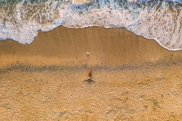 Vue aérienne de haut en bas d'une femme allongée sur une plage de sable de la plage de Milos, l'île de Lefkada, Grèce