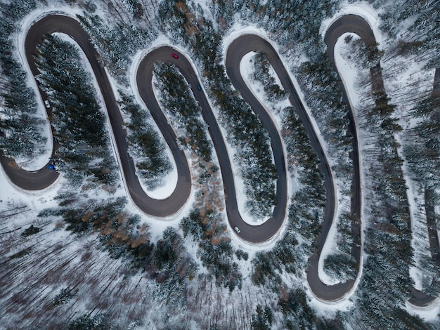 Vue aérienne de haut en bas de la route sinueuse d'hiver dans la forêt Transylvanie Roumanie