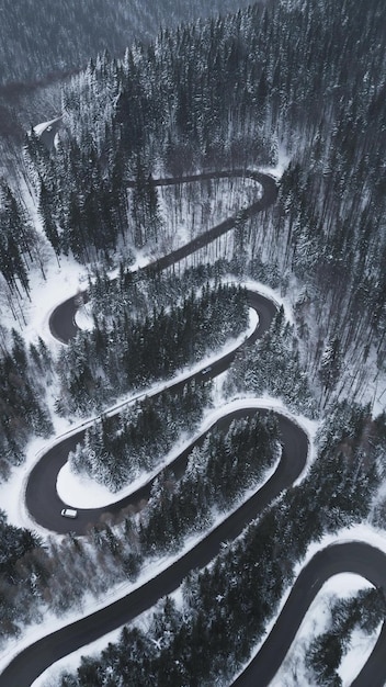 Vue aérienne de haut en bas de la route sinueuse d'hiver dans la forêt Transylvanie Roumanie