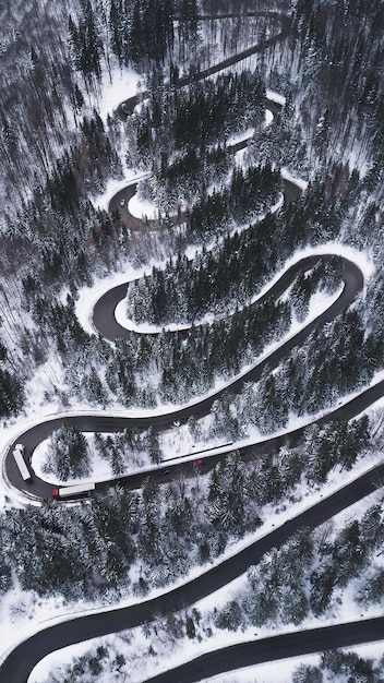 Vue aérienne de haut en bas de la route sinueuse d'hiver dans la forêt Transylvanie Roumanie