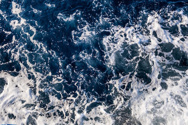 Vue aérienne de haut en bas de la surface de l'eau de mer. Texture de vagues de mousse blanche comme fond naturel.