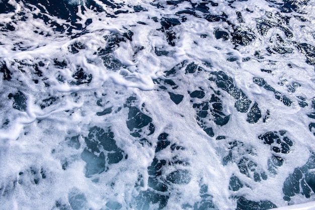 Vue aérienne de haut en bas de la surface de l'eau de mer. Texture de vagues de mousse blanche