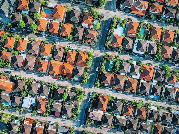 Vue aérienne de haut en bas survolant la ville montrant des maisons familiales de quartier immobilier avec des toits et des jardins rouge orange