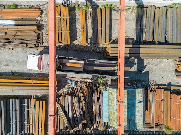 Vue aérienne de haut en bas des travailleurs chargeant une pile de tuyaux métalliques avec un portique