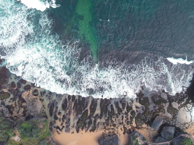 Vue aérienne de haut en bas des vagues géantes de l'océan qui s'écrasent et écument sur la plage de corail