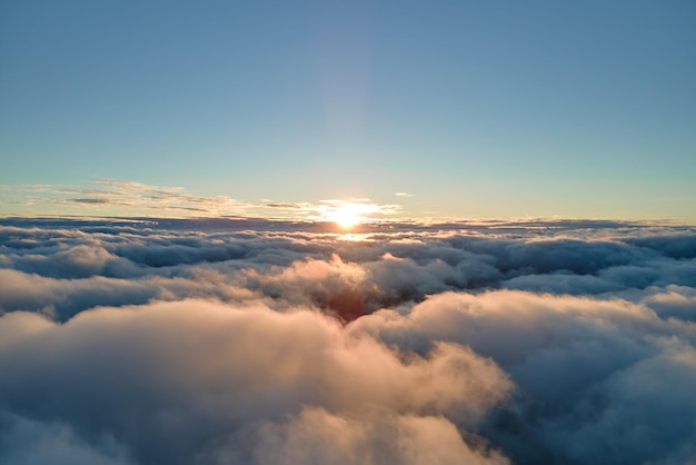 Vue aérienne d'en haut à haute altitude de denses cumulus gonflés volant en soirée Incroyable coucher de soleil du point de vue de la fenêtre de l'avion