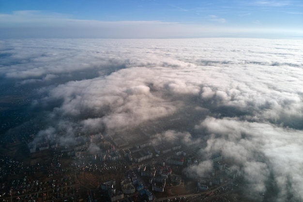 Vue aérienne de la haute altitude de la ville lointaine couverte de cumulus gonflés volant par avant l'orage Point de vue de l'avion du paysage par temps nuageux