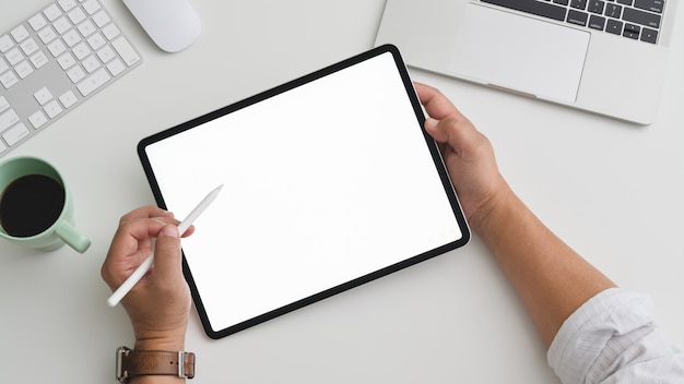 Vue aérienne d'homme d'affaires travaillant sur tablette dans un espace de travail pratique avec ordinateur et ordinateur portable