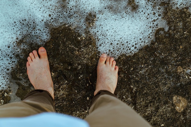 Vue aérienne de l'homme marchant pieds nus au bord de la mer plage rocheuse