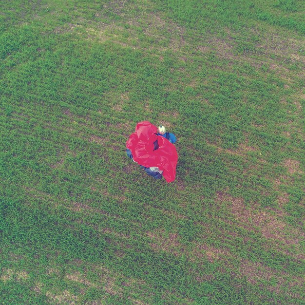 Vue aérienne de l'homme avec un parapluie rouge sur un champ vert