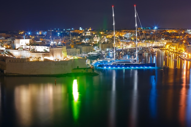 Vue aérienne sur l'horizon des anciennes défenses de Birgu et du fort Saint-Ange, vues de La Valette la nuit, Malte.