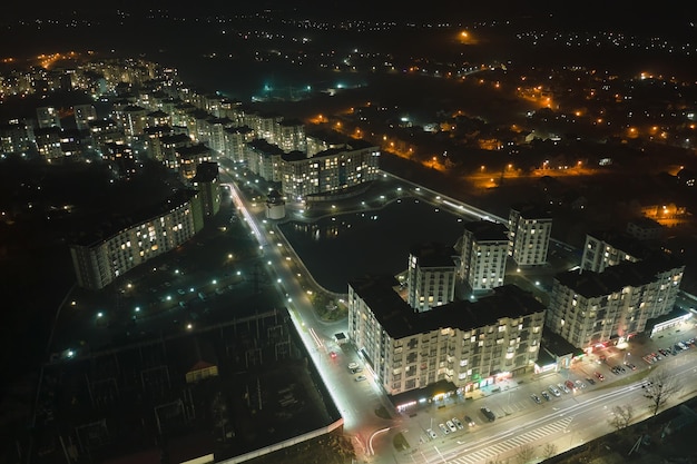 Vue aérienne des immeubles d'habitation de grande hauteur et des rues illuminées dans le quartier résidentiel de la ville la nuit. Paysage urbain sombre.