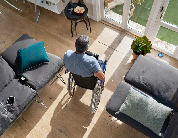 Photo vue aérienne d'un individu d'âge moyen dans un salon retourné à l'aide d'une aide à la mobilité navigant...