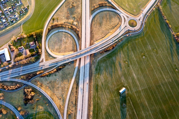 Vue aérienne de l'intersection de la route moderne, les toits des maisons sur fond de champ vert de printemps. Photographie de drone.