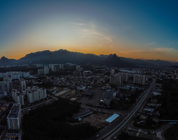 Vue aérienne de Jacarepagua à Rio de Janeiro Brésil Bâtiments résidentiels et montagnes en arrière-plan Journée ensoleillée Coucher de soleil Drone photo