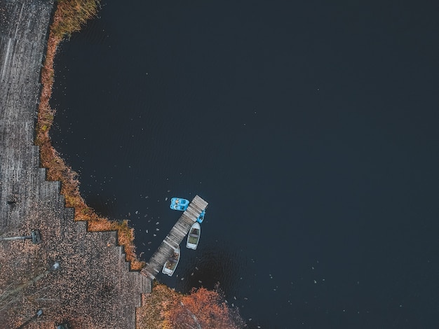 Vue aérienne de la jetée avec des bateaux en bois au bord d'un lac pittoresque, forêt d'automne. Saint-Pétersbourg, Russie.