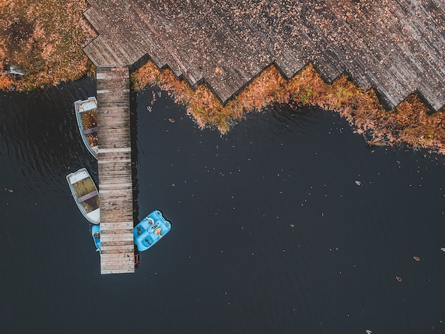 Vue aérienne de la jetée avec des bateaux en bois au bord d'un lac pittoresque, forêt d'automne. Saint-Pétersbourg, Russie.