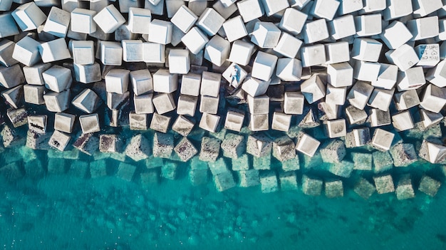 Vue aérienne d'un jeune homme sur un bloc de cubes de ciment protégeant le rivage des vagues dans le port de Malaga, en Espagne.