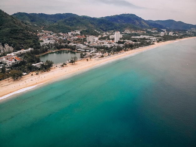 Vue aérienne de la longue plage de sable, des palmiers, de la ville côtière avec des hôtels, des collines et du bord de mer ; concept de pays exotique.