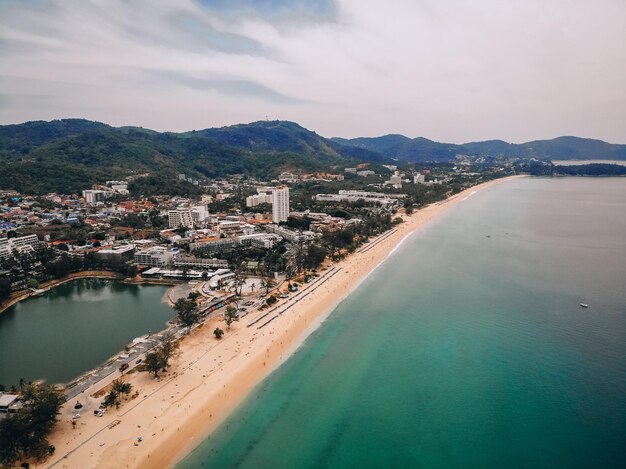 Vue aérienne de la longue plage de sable, des palmiers, de la ville côtière avec des hôtels, des collines et du bord de mer ; concept de pays exotique.
