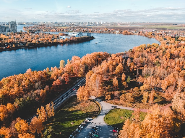 Vue aérienne sur les lumières du matin dans la forêt. Arbres colorés et lac bleu d'en haut, route sinueuse. Russie, Saint-Pétersbourg