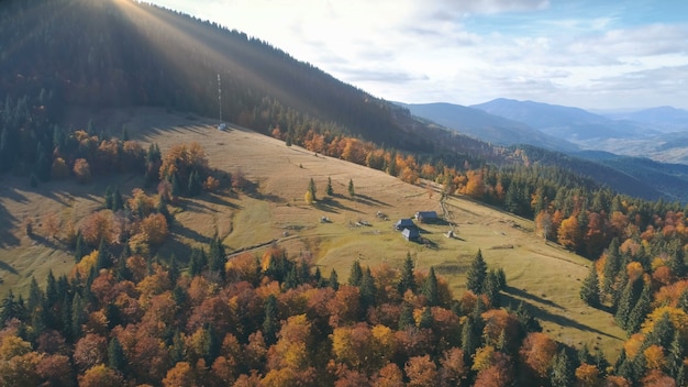 Vue aérienne sur le magnifique paysage de montagne d'automne pâturage jaune avec des maisons solitaires parmi l'orange