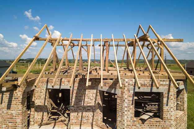 Vue aérienne de la maison inachevée avec structure à ossature de toit en bois en construction.