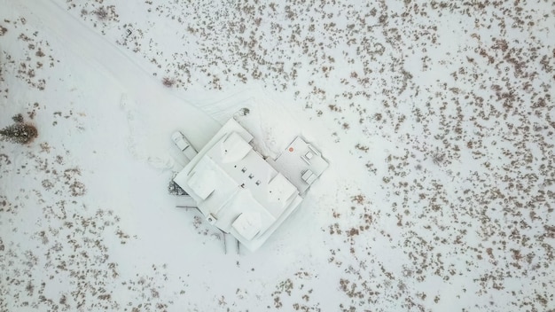 Vue aérienne de la maison de montagne recouverte de neige en hiver.