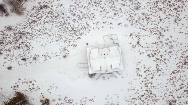 Vue aérienne de la maison de montagne recouverte de neige en hiver.