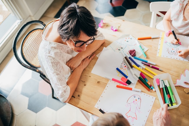 Vue aérienne mère dessin à l'intérieur avec un crayon de couleur avec ses enfants