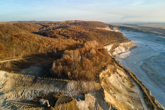 Vue aérienne de la mine à ciel ouvert de matériaux de grès pour l'industrie de la construction avec des excavatrices et des camions à benne basculante. Équipement lourd dans l'exploitation minière et la production de concept de minéraux utiles.