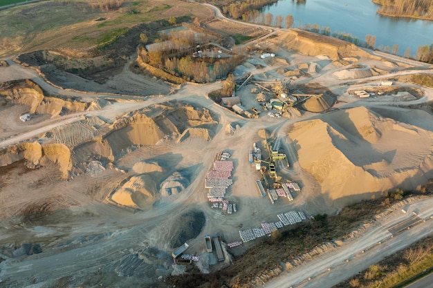 Vue aérienne de la mine à ciel ouvert de matériaux de grès pour l'industrie de la construction avec des excavatrices et des camions à benne basculante Équipement lourd dans l'exploitation minière et la production de concept de minéraux utiles