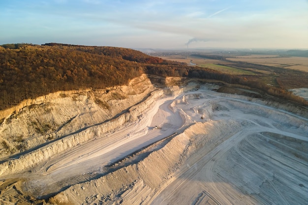 Vue aérienne de la mine à ciel ouvert de matériaux de grès pour l'industrie de la construction avec des excavatrices et des camions à benne basculante. Équipement lourd dans l'exploitation minière et la production de minéraux utiles concept