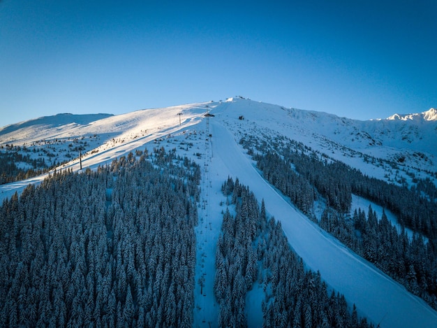 Vue aérienne des montagnes aux sommets enneigés contre le ciel bleu clair