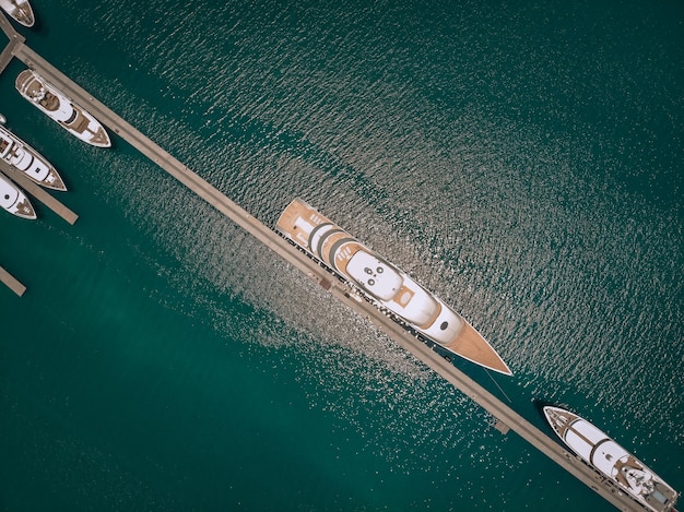 Vue aérienne des nombreux yachts blancs de première classe amarrés au quai, océan turquoise par une journée ensoleillée ; concept de luxe.